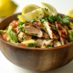 A delicious avocado chicken salad in a wooden bowl with fresh ingredients.