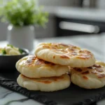 Close-up of freshly baked mini naan bread on a slate board with garlic butter in a modern kitchen