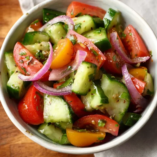 Fresh cucumber tomato salad with red onion and herbs in a ceramic bowl