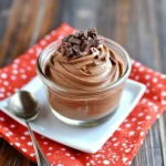 Easy Chocolate Mousse in a glass jar topped with piped cream and chocolate shavings.