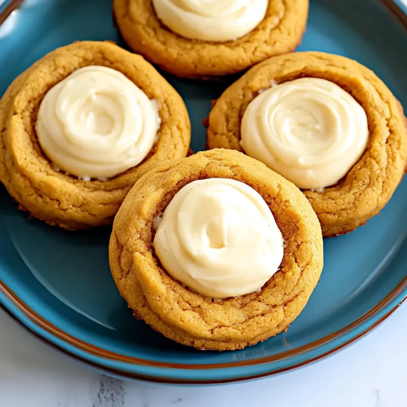 Freshly baked pumpkin cheesecake cookies with creamy cheesecake filling, served on a blue plate, perfect fall dessert.