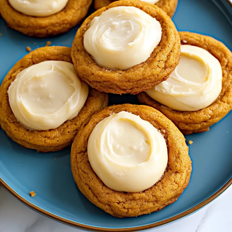 Pumpkin cheesecake cookies with creamy cheesecake filling served on a blue plate, soft spiced cookies perfect for Thanksgiving dessert.