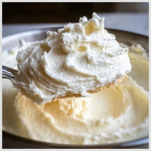 A spoonful of creamy, white 300 Dollar Frosting Recipe, showing its rich texture and swirls.