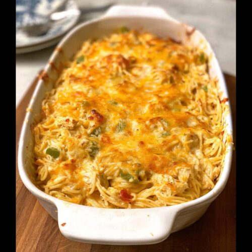 A golden-brown baked Creamy Southern Chicken Spaghetti Casserole in a white dish, topped with melted cheese.