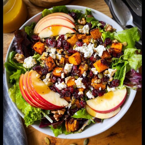 A vibrant Fall Harvest Salad with Cranberries, featuring roasted butternut squash, apple slices, feta cheese, and walnuts.
