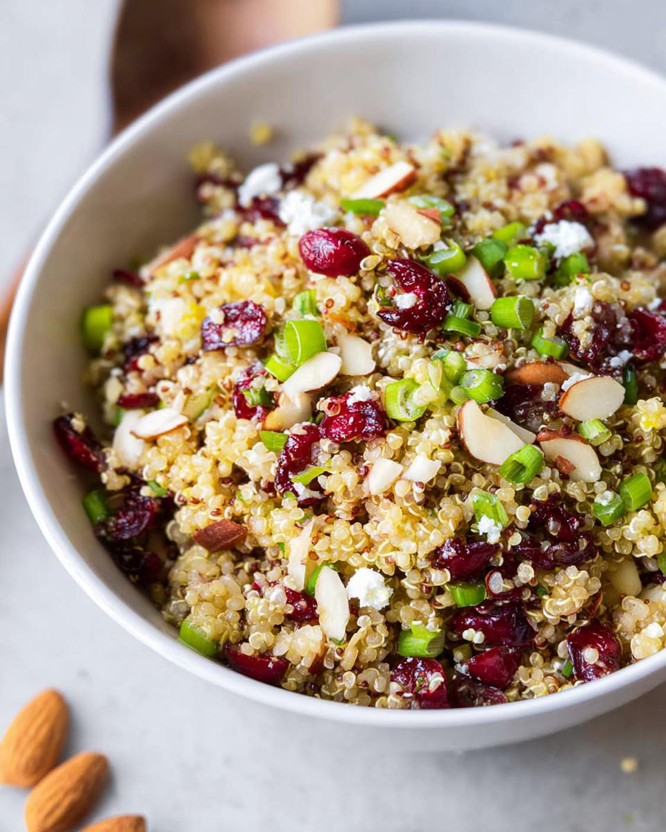 A close-up of a Quinoa Cranberry Bowl, featuring quinoa, dried cranberries, almonds, feta cheese, and green onions.