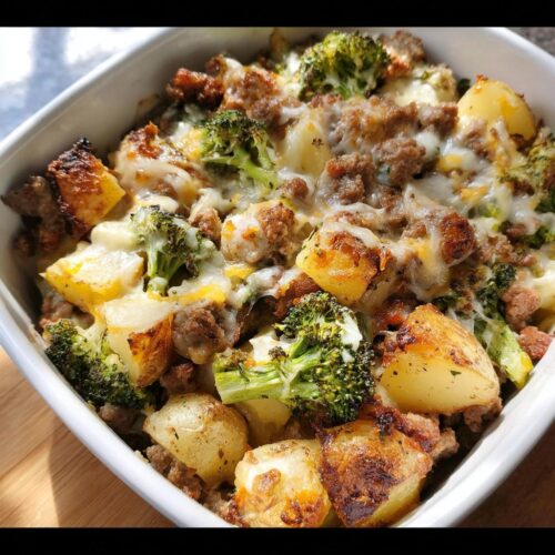 Close-up of a white baking dish filled with Ranch Baked Potatoes with Sausage & Broccoli, topped with melted cheese.