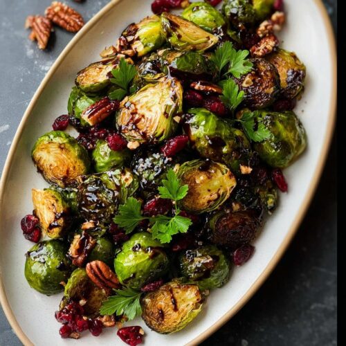 Close-up of crispy roasted Brussels sprouts with balsamic glaze, dried cranberries, pecans, and parsley.