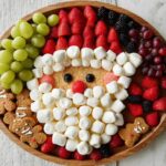A whimsical Santa Fruit Tray made with grapes, strawberries, marshmallows, and gingerbread cookies.