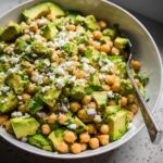 A close-up of a vibrant Avocado Chickpea Bowl featuring diced avocado, chickpeas, feta cheese, and cilantro.
