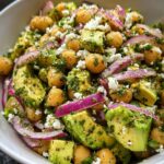 Close-up of a vibrant Chickpea Feta Avocado Salad featuring chickpeas, cubed avocado, red onion slices, and crumbled feta.
