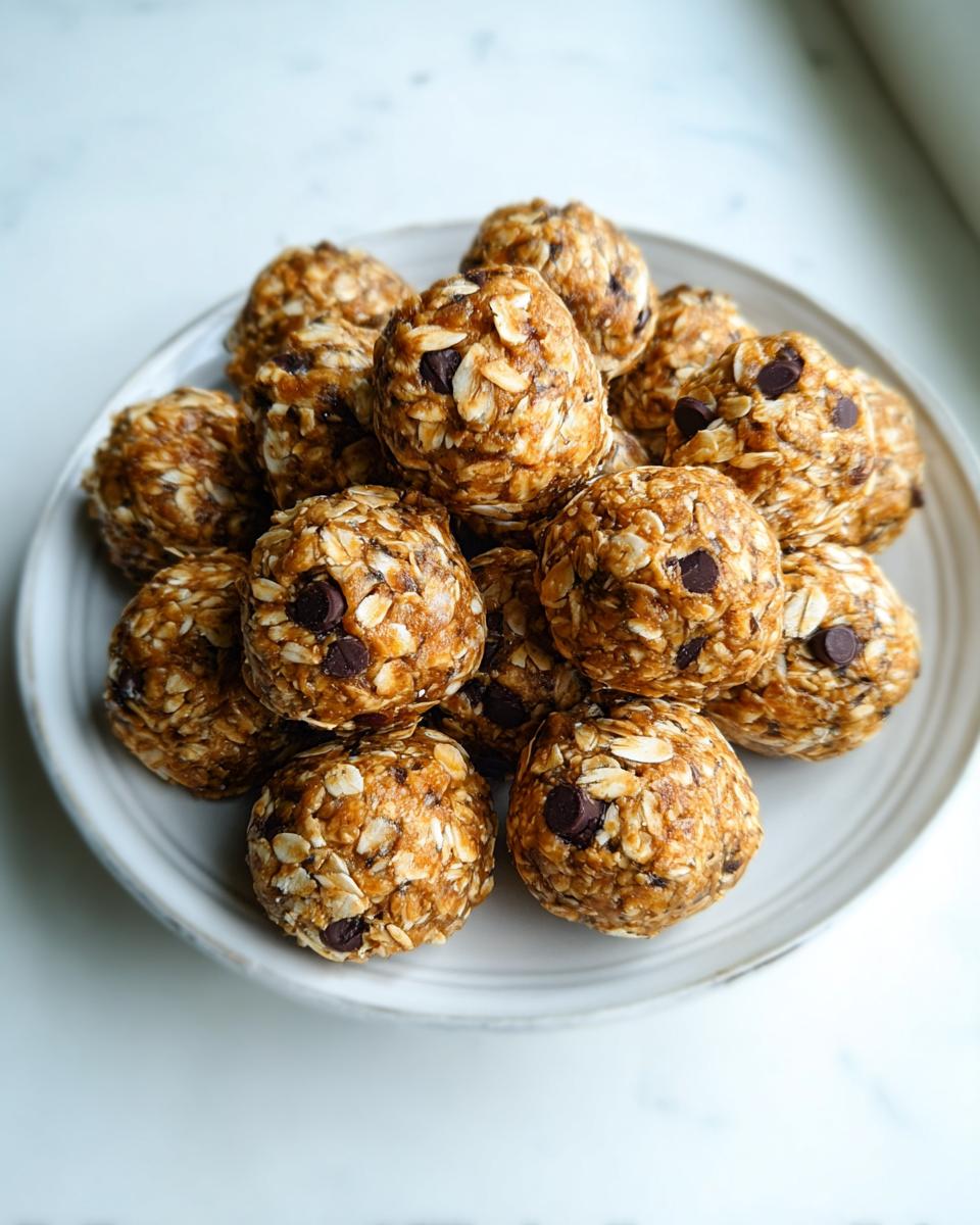 A mound of freshly made Healthy Energy Bites studded with visible oats and mini chocolate chips, served on a white plate.