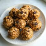 A close-up overhead shot of several chocolate chip Healthy Energy Bites stacked on a light-colored plate.