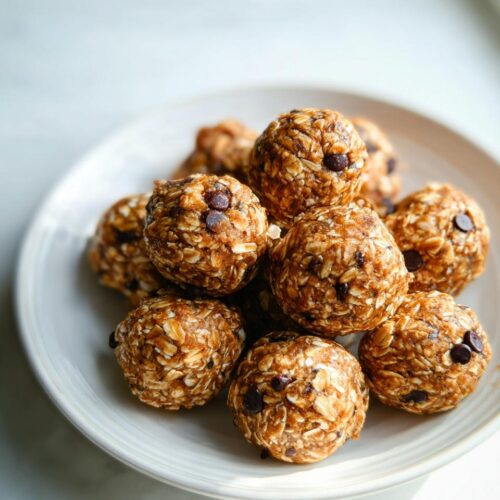 A close-up of several chocolate chip Healthy Energy Bites stacked on a white plate.