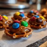 Close-up of several 3-ingredient Christmas Pretzel Treats topped with caramel and colorful M&Ms.