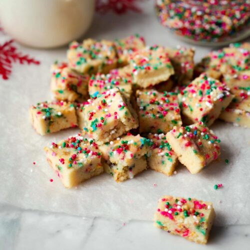 A pile of festive Confetti Holiday Shortbread cookies, sprinkled with colorful jimmies and nonpareils.
