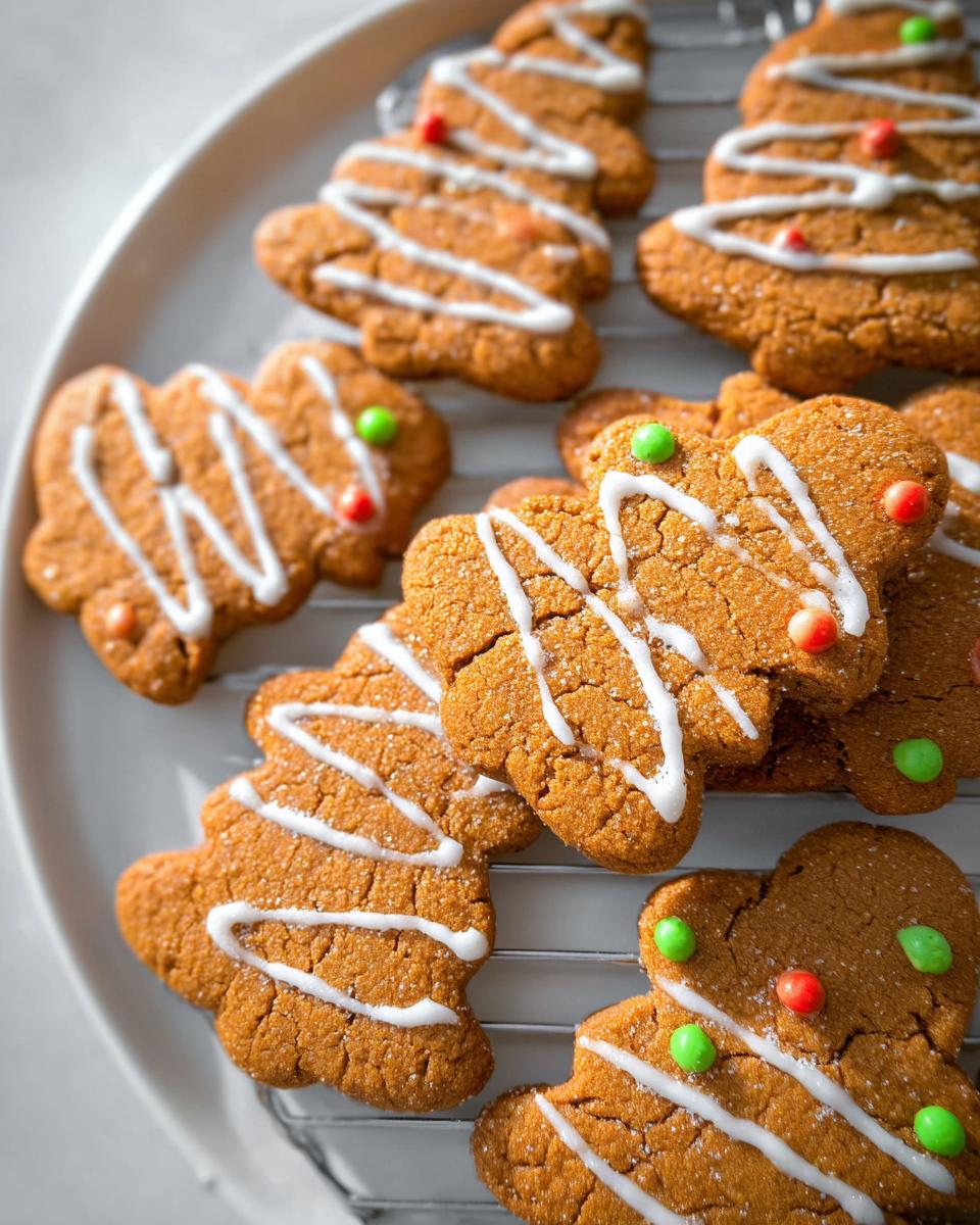 Close-up of festive Crispy Gingerbread Cookies shaped like gingerbread men and trees, decorated with white icing and colorful candies.