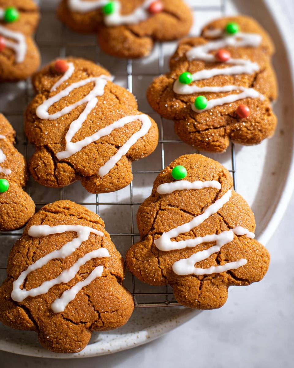 Close-up of freshly baked Crispy Gingerbread Cookies decorated with white icing and colorful candies on a cooling rack.