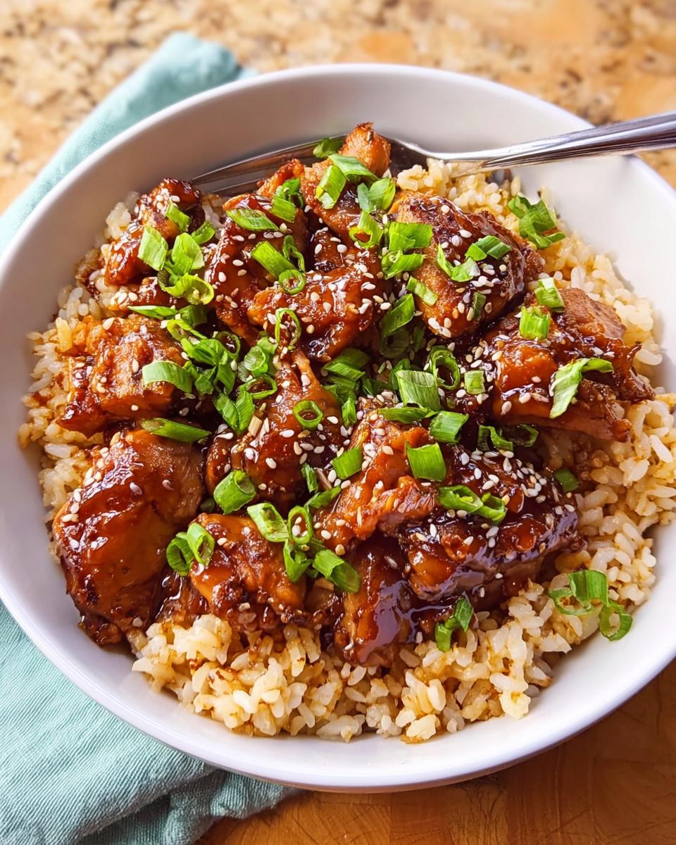 Close-up of Crockpot Teriyaki Chicken with Rice, topped with sesame seeds and green onions.