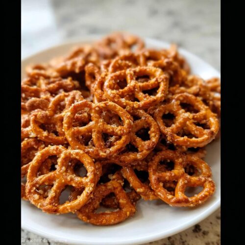 A pile of crunchy, seasoned pretzels on a white plate, perfect for an Easy Pretzel Snack Recipe.