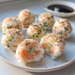 A plate featuring several Easy Sushi Balls filled with salmon and cucumber, topped with toasted sesame seeds.