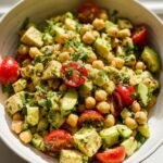 Close-up of a bowl filled with High Protein Chickpea Salad featuring avocado chunks, cherry tomatoes, and tofu cubes.