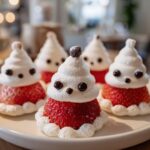 Close-up of adorable Mini Strawberry Santas for Kids, made with strawberries and whipped cream, on a white plate.