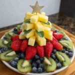 A festive Pineapple Christmas Tree Platter featuring pineapple chunks, strawberries, blueberries, and kiwi slices, topped with a star.