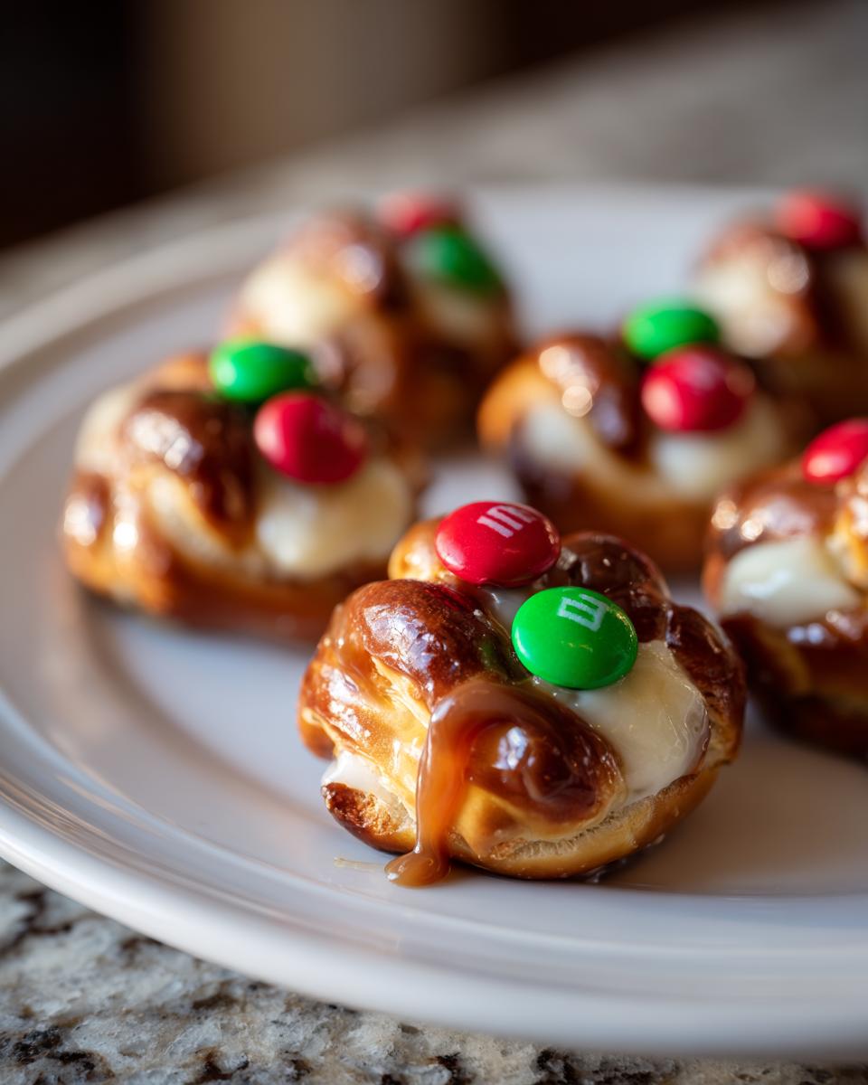 Close-up of Rolo Christmas Candy Bites topped with white frosting, caramel drizzle, and red and green M&Ms.