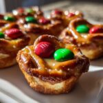 Close-up of Rolo Christmas Candy Bites topped with red and green M&Ms and drizzled with caramel.