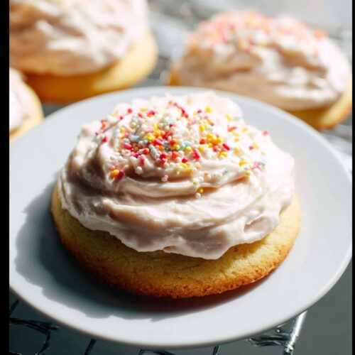 Close-up of a soft sugar cookie topped with thick Bakery-Style Sugar Cookie Frosting and colorful sprinkles.