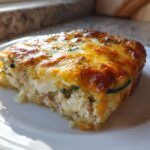 A close-up of a serving of baked Chicken Zucchini Casserole with a golden, melted cheese topping.