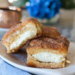 Two halves of a Churro Cheesecake Bite showing the creamy white filling inside, coated in cinnamon sugar.