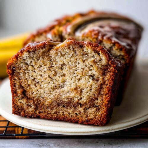 Close-up of a moist slice of Cinnamon Banana Brunch Loaf showing the swirl and light glaze topping.