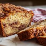 A loaf of Cinnamon Streusel Banana Bread with two slices cut, showing the moist interior and crunchy topping.
