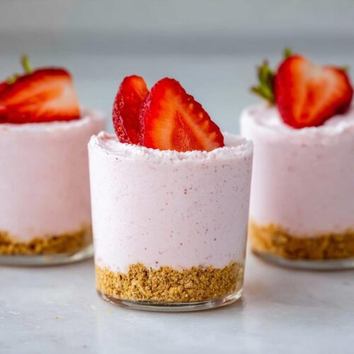 Three individual Creamy Strawberry Mousse Cups featuring a graham cracker crust and fresh strawberry slices on top.