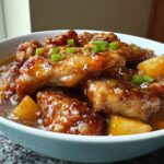 Close-up of glazed chicken pieces with pineapple chunks in a savory sauce, garnished with green onions, ready for a Dump and Go Asian Chicken Dinner.
