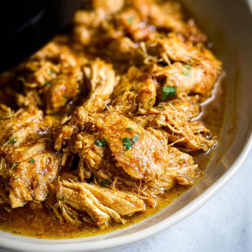 Close-up of tender, shredded chicken coated in a savory sauce, ready to serve from the Easy Garlic Chicken Crockpot Recipe.