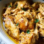 Close-up of tender, shredded chicken coated in a savory sauce from the Easy Garlic Chicken Crockpot Recipe, garnished with parsley.
