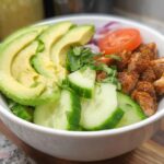 Close-up of an Easy Keto Lunch Idea bowl featuring seasoned chicken, sliced avocado, cucumber, and tomato.
