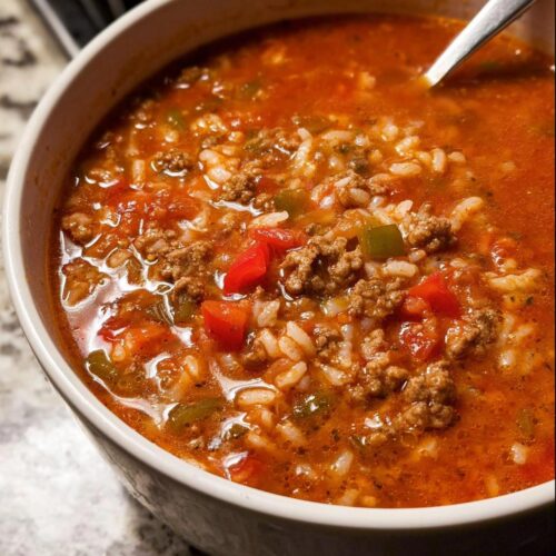 Close-up of a steaming bowl of Easy Stuffed Pepper Soup with ground beef, rice, and diced peppers in a rich tomato broth.