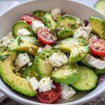 Close-up of a vibrant Feta & Avocado Lunch Bowl featuring sliced avocado, feta cheese cubes, and cherry tomatoes dressed with herbs.