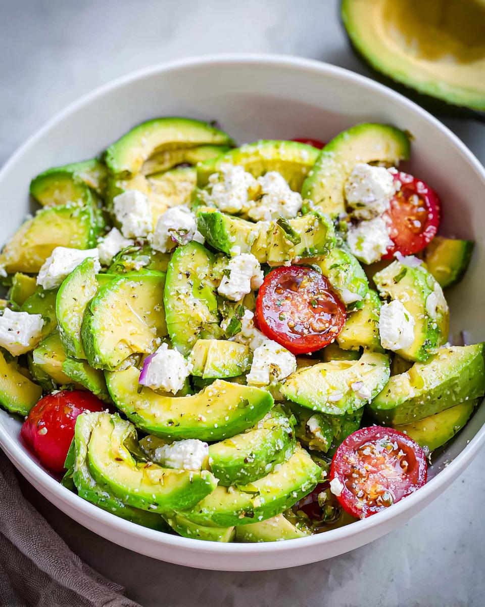 Close-up of a vibrant Feta & Avocado Lunch Bowl featuring sliced avocado, cherry tomatoes, and crumbled feta cheese.