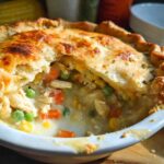 Close-up of a freshly baked Freezer-Friendly Chicken Pot Pie with a flaky golden crust broken open to show creamy chicken and vegetable filling.