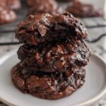 A stack of three rich, fudgy Flourless Chocolate Cookies piled on a small white plate.