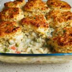 Close-up of a baked Garlic Herb Biscuit Chicken Pot Pie with golden biscuits topping creamy filling in a glass dish.