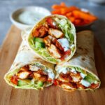Two halves of freshly made Grilled Chicken Wraps filled with seasoned chicken, lettuce, cucumber, and white sauce.