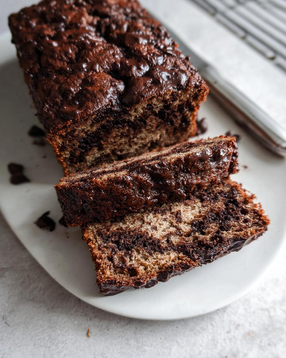 Close-up of sliced Healthy Chocolate Banana Bread with a rich, marbled chocolate swirl and glossy topping.