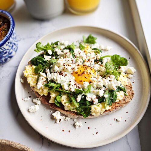 Close-up of a Healthy Egg Breakfast with Feta, featuring scrambled eggs, spinach, and a runny yolk topped with crumbled feta.