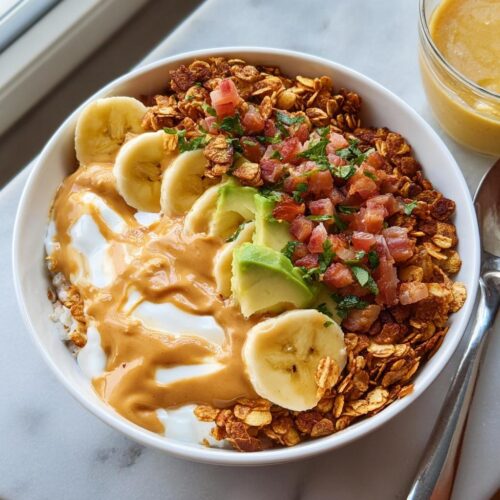A vibrant High-Protein Breakfast Bowl topped with yogurt, peanut butter, banana slices, avocado, and savory bacon bits.